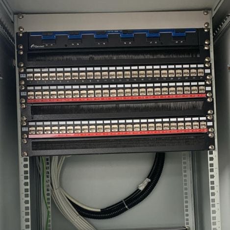 A network cabinet from Tal Systems, designed for corporate server farms, that includes connection boards, Ethernet ports, neat and organized white cables, and a black cable duct at the bottom.
