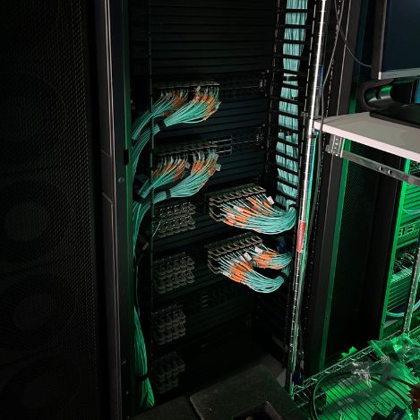 A server cabinet with carefully arranged cables connected to several connection boards in a data center, showcasing Tal Systems, experts in server farm building solutions for companies.